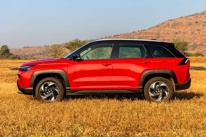 Maruti Suzuki Victoris in red with black roof, left side view on grass Maruti Suzuki Victoris in red with black roof, left side view on grass