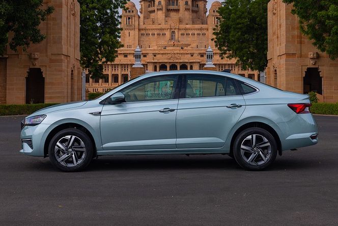 Skoda Slavia in light blue-grey, left side profile, parked before a palace. Skoda Slavia in light blue-grey, left side profile, parked before a palace.