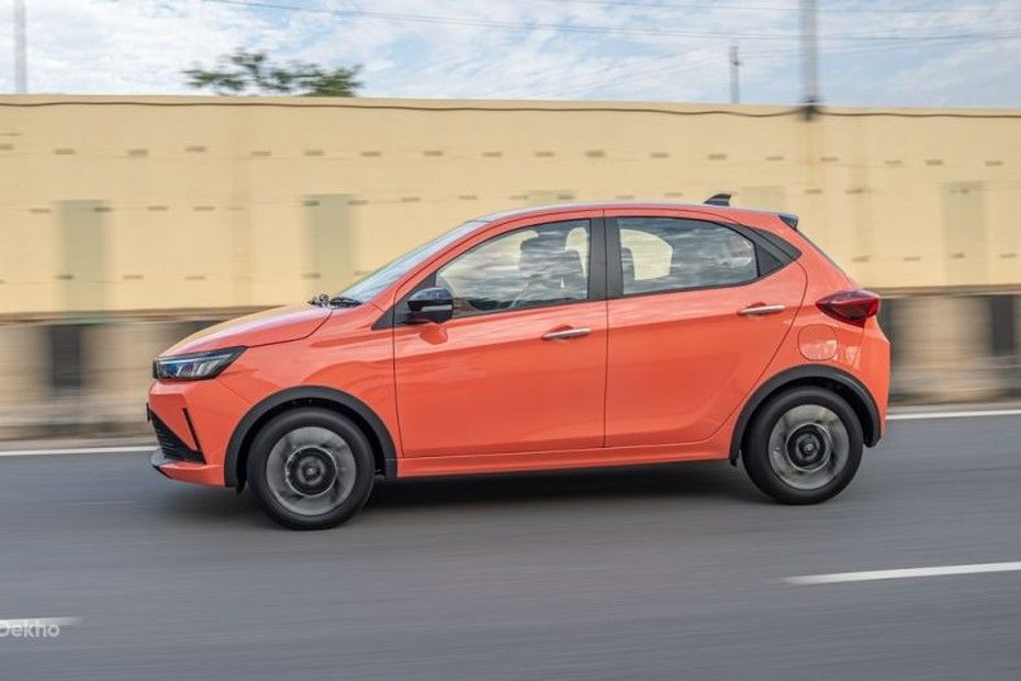 Tata Tiago in orange driving on a highway, side view