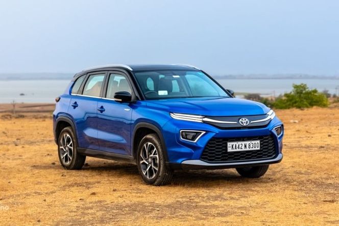 Toyota Hyryder in blue parked on dry grassland, front three-quarter view Toyota Hyryder in blue parked on dry grassland, front three-quarter view