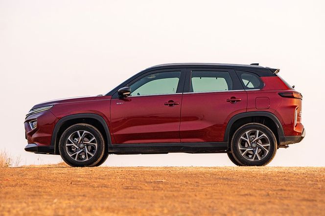 Toyota Hyryder in red with black roof, left side profile on dirt ground Toyota Hyryder in red with black roof, left side profile on dirt ground