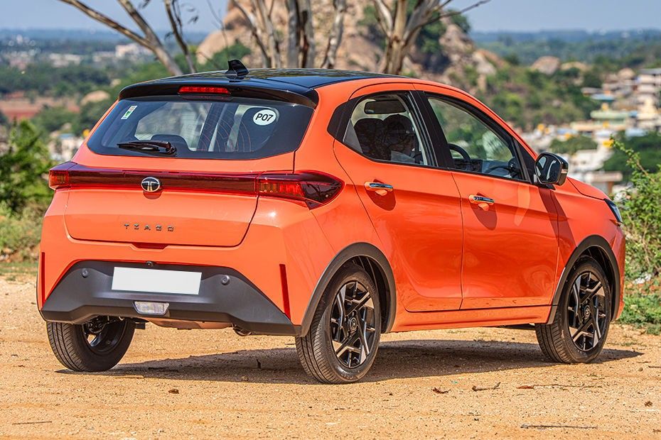 Tata Tiago in orange with black roof, seen from rear three-quarter angle