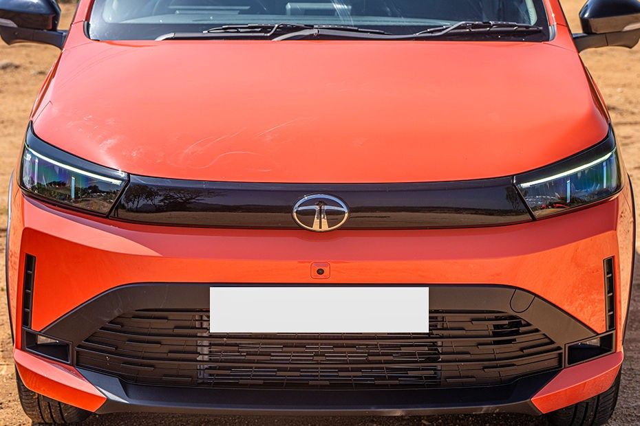 Tata Tiago front end in orange showing slim LED DRLs and wide lower grille
