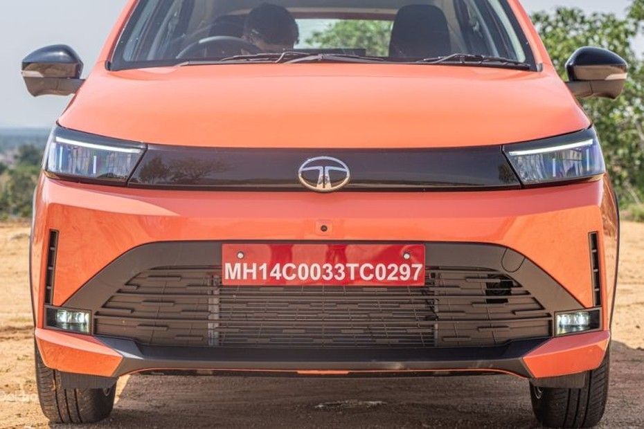 Tata Tiago front view in orange showing LED headlamps, wide grille and fog lamps