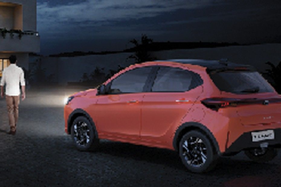 Tata Tiago parked at night, headlamps lighting the path for a walking owner